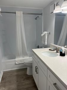 a white bathroom with a sink and a toilet at Summer Sands - 307 by Sea Scape Properties in Wrightsville Beach