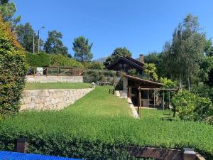 ein Garten mit einer Steinmauer und einem Gebäude in der Unterkunft Chalé do Pinheiro in Cortes