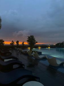 a group of chairs sitting next to a pool at sunset at Stylish 1BR Near Airport Facing the Bay - 9d in Manila