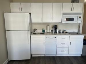 a kitchen with white cabinets and a white refrigerator at Summer Sands - 408 by Sea Scape Properties in Wrightsville Beach
