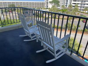 a pair of chairs sitting on a balcony at Summer Sands - 408 by Sea Scape Properties in Wrightsville Beach +2 photos