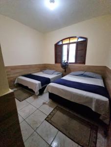 ein Schlafzimmer mit zwei Betten und einem Fenster in der Unterkunft Casa completa a 300 mts da praia in Itanhaém