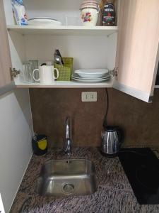 a kitchen counter with a sink and plates on a shelf at Apartahotel Ave Paraiso in Cochabamba