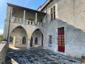 a building with a red door and a stone courtyard at Suite de charme au château de Cibioux in Surin