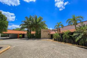 an empty driveway in front of a building with palm trees at Hotel Ciudad Real Palenque in Palenque
