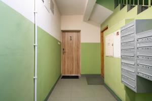 a hallway with green walls and a wooden door at Patro Apartament 2 Wrocław Centrum in Wrocław