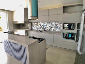 eine Küche mit weißen Schränken und einem Herd mit Backofen in der Unterkunft Casa de Luxo Decorada no Condomínio La Plage in Xangri-lá + 12 Fotos