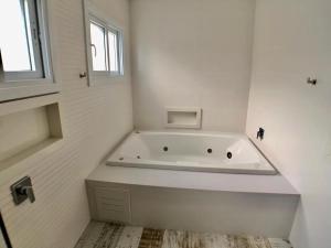 eine weiße Badewanne in einem Badezimmer mit Fenster in der Unterkunft Casa de Luxo Decorada no Condomínio La Plage in Xangri-lá
