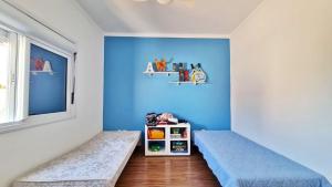 Cette chambre bleue comprend 2 lits et une fenêtre. dans l'établissement Casa de Verão dos Sonhos no Las Palmas, à Xangri-lá