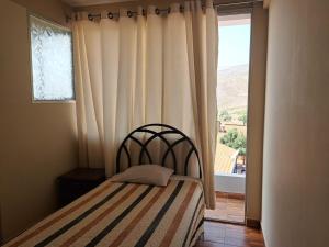 a bedroom with a bed and a large window at Hostal Edén in Torotoro