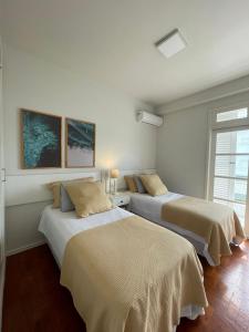 two beds in a room with white walls at Beira-Mar de Atlântida: Conforto Completo in Xangri-lá