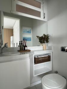 a white bathroom with a toilet and a sink at Beira-Mar de Atlântida: Conforto Completo in Xangri-lá