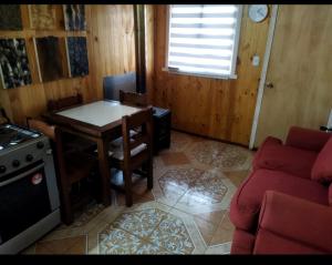 ein Wohnzimmer mit einem Tisch und einem Herd in der Unterkunft Cabañas la tía Julia in Melipeuco
