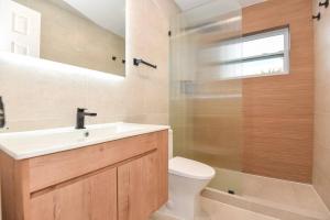 Un baño con lavabo, inodoro y ducha. en Magical beach bungalow getaway!, en Ormond-by-the-Sea