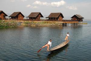 two men are on a canoe in the water at Golden Island Cottages Nampan in Ywama