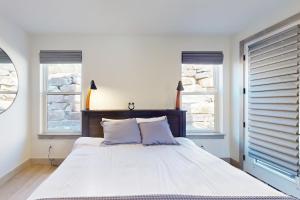 a bedroom with a large white bed with two windows at Rendezvous Retreat in Fraser