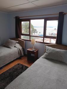 une chambre avec deux lits et une fenêtre dans l'établissement Casa Colores, à Puerto Montt