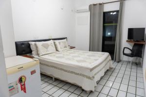a small bedroom with a bed and a tv at Pousada Girassol in Rio das Ostras