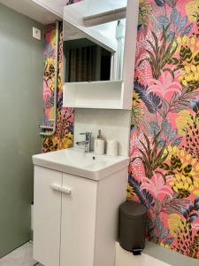 a bathroom with a sink and a flower wallpaper at Loft avec parking centre Tours et bord du Cher Loire Valley in Tours +8 photos