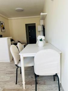 Una mesa blanca con sillas blancas y un jarrón con flores. en Ivy Central Residence, en Baia Mare