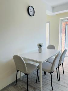 Una mesa de comedor con sillas y un reloj en la pared. en Ivy Central Residence, en Baia Mare