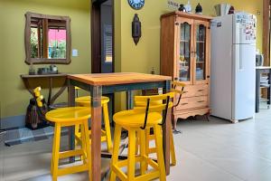 a kitchen with a wooden table and yellow stools at Casa Charme no Centro de Bonito - Condomínio Eco Bonito in Bonito +25 photos