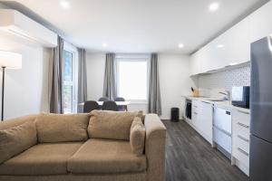 a living room with a couch and a kitchen at Modern Central Apartment, Flexible Bed Options in Dunedin