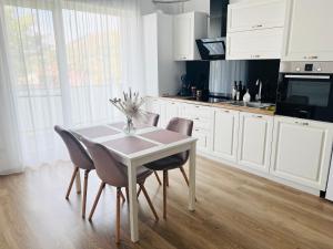 a kitchen with white cabinets and a table and chairs at Grandview Central Residence in Baia Mare