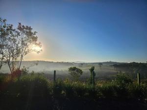 una vista de un campo con la puesta de sol a lo lejos en Chácara Pôr do Sol, en Campo Alegre 3 fotos más