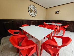 Una habitación con sillas y mesas rojas y un reloj. en Hostel La Cali Inn, en San José