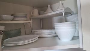 a kitchen shelf with plates and bowls and a sink at Beralmar in Asilah