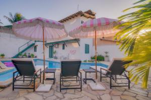 a group of chairs and umbrellas next to a pool at Elsi Pousada in Búzios