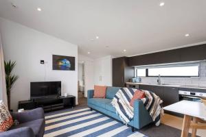 a living room with a blue couch and a kitchen at Luxury Sunny Warm CBD at Doorstep in Linwood