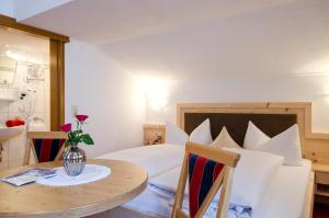 Un dormitorio con una cama y una mesa con un jarrón de flores. en Apart Petra, en Galtür