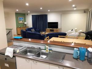 a kitchen with a sink and a living room at Karma Waters Beach House, 100m from beach in Middleton