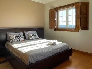 een slaapkamer met een groot bed en een raam bij Cantinho do Minho - Ponte de Lima in Ponte de Lima