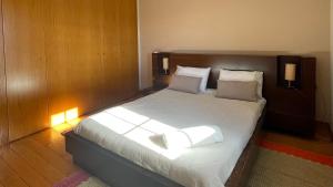 a bedroom with a large bed with white sheets at Cantinho do Minho - Ponte de Lima in Ponte de Lima