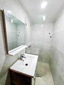 a white bathroom with a sink and a mirror at Luxury Apartment Fes - Family Suites in Fès