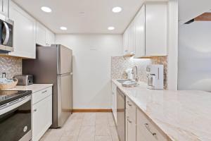 a kitchen with white cabinets and stainless steel appliances at Lodge at Lionshead 270 in Vail