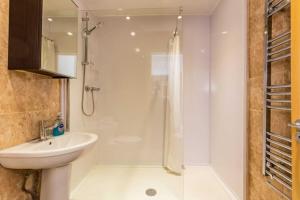a white bathroom with a shower and a sink at Midas Lodge in Newcastle upon Tyne