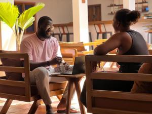 a man and a woman sitting at a table with a laptop at Fly Fishes Hotel in Saint-Louis