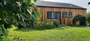 a wooden house with a garden in front of it at Pohutukawa Cottage in Ohope Beach