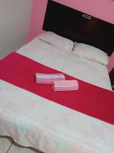 a bed with two pink and white sheets and pillows at Pousada Paradise in Rio Grande