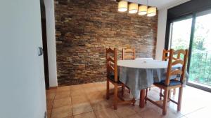 a dining room with a table and chairs and a brick wall at Piso rural Sol Berguedà in Aviá