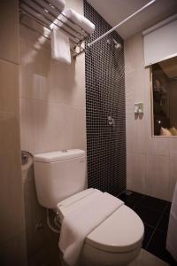 La salle de bains est pourvue d'une douche et de toilettes blanches. dans l'établissement Happy Inn, à Jakarta