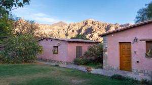 two pink houses with a mountain in the background at Hosteria La Morada in Tilcara
