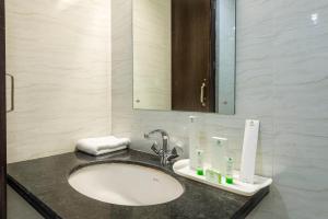 ein Bad mit einem Waschbecken und einem Spiegel in der Unterkunft Hotel Raya Inn in Jaipur