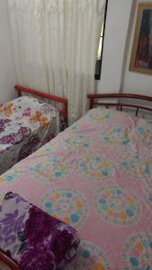 ein Schlafzimmer mit zwei Betten und einer rosa-blauen Bettdecke in der Unterkunft Cabaña Villa Gabi in San Antero