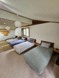 a bedroom with two beds and two tables at Yamadasan Ski Lodge - Madarao in Madarao Kogen