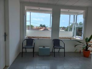 two chairs and a table in a room with two windows at Tanjung Residence16 Syariah in Kampungdurian